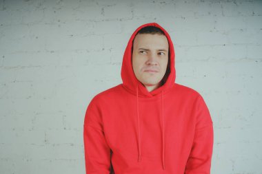 Yakışıklı olan bir tuğla duvar tarafından poz. Kırmızı kapüşonlu deli adam