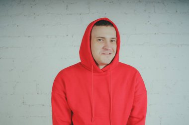 Yakışıklı olan bir tuğla duvar tarafından poz. Kırmızı kapüşonlu deli adam