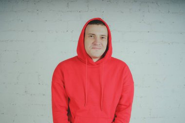 Yakışıklı olan bir tuğla duvar tarafından poz. Kırmızı kapüşonlu deli adam