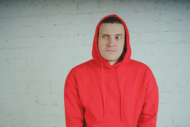 Yakışıklı olan bir tuğla duvar tarafından poz. Kırmızı kapüşonlu deli adam