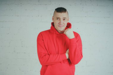 Yakışıklı olan bir tuğla duvar tarafından poz. Kırmızı kapüşonlu deli adam