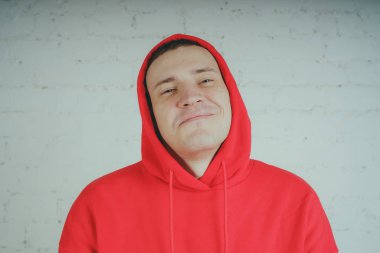 Yakışıklı olan bir tuğla duvar tarafından poz. Kırmızı kapüşonlu deli adam