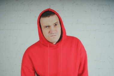 Yakışıklı olan bir tuğla duvar tarafından poz. Kırmızı kapüşonlu deli adam