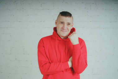 Yakışıklı olan bir tuğla duvar tarafından poz. Kırmızı kapüşonlu deli adam