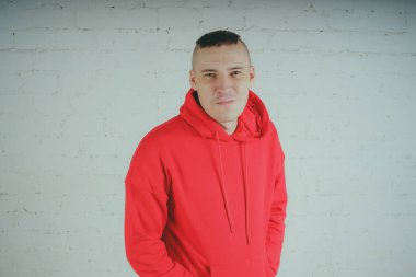 Yakışıklı olan bir tuğla duvar tarafından poz. Kırmızı kapüşonlu deli adam