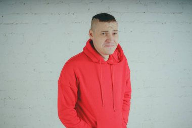 Yakışıklı olan bir tuğla duvar tarafından poz. Kırmızı kapüşonlu deli adam