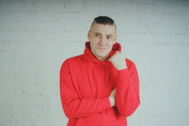 Yakışıklı olan bir tuğla duvar tarafından poz. Kırmızı kapüşonlu deli adam