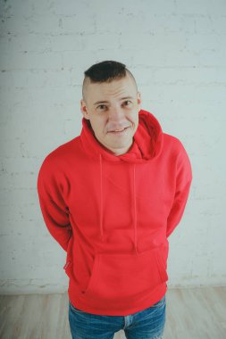 Yakışıklı olan bir tuğla duvar tarafından poz. Kırmızı kapüşonlu deli adam