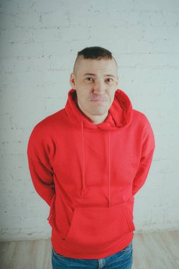 Yakışıklı olan bir tuğla duvar tarafından poz. Kırmızı kapüşonlu deli adam