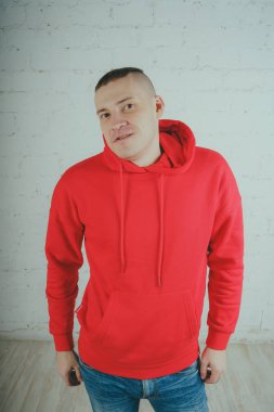 Yakışıklı olan bir tuğla duvar tarafından poz. Kırmızı kapüşonlu deli adam