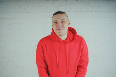 Yakışıklı olan bir tuğla duvar tarafından poz. Kırmızı kapüşonlu deli adam