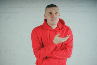 Yakışıklı olan bir tuğla duvar tarafından poz. Kırmızı kapüşonlu deli adam
