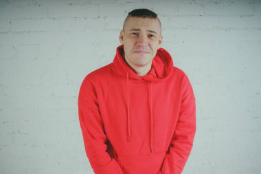 Yakışıklı olan bir tuğla duvar tarafından poz. Kırmızı kapüşonlu deli adam