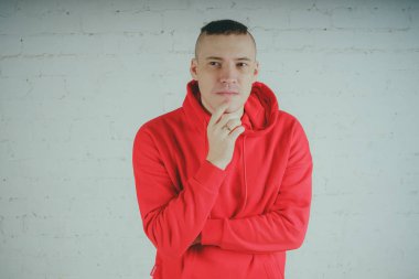 Yakışıklı olan bir tuğla duvar tarafından poz. Kırmızı kapüşonlu deli adam