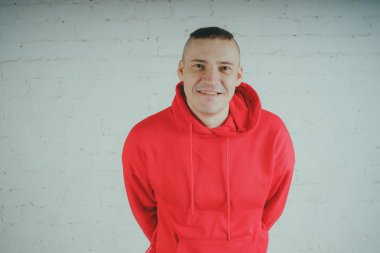 Yakışıklı olan bir tuğla duvar tarafından poz. Kırmızı kapüşonlu deli adam