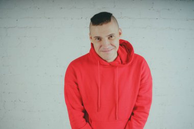 Yakışıklı olan bir tuğla duvar tarafından poz. Kırmızı kapüşonlu deli adam