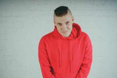 Yakışıklı olan bir tuğla duvar tarafından poz. Kırmızı kapüşonlu deli adam