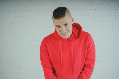 Yakışıklı olan bir tuğla duvar tarafından poz. Kırmızı kapüşonlu deli adam