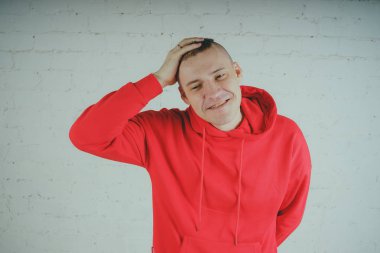 Yakışıklı olan bir tuğla duvar tarafından poz. Kırmızı kapüşonlu deli adam