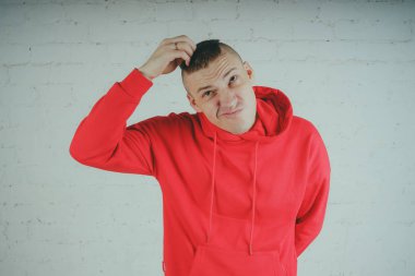 Yakışıklı olan bir tuğla duvar tarafından poz. Kırmızı kapüşonlu deli adam