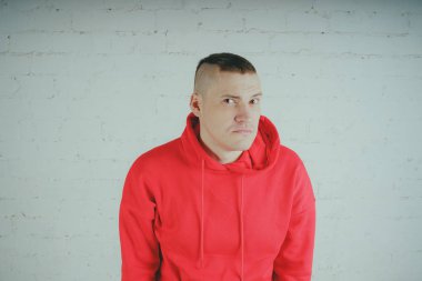 Yakışıklı olan bir tuğla duvar tarafından poz. Kırmızı kapüşonlu deli adam