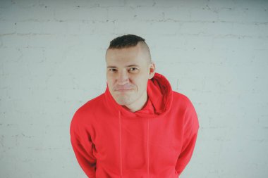 Yakışıklı olan bir tuğla duvar tarafından poz. Kırmızı kapüşonlu deli adam