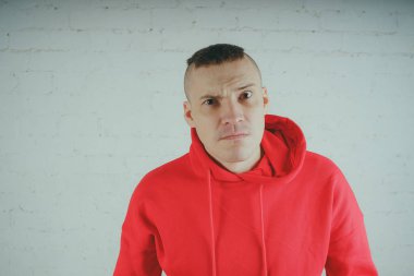 Yakışıklı olan bir tuğla duvar tarafından poz. Kırmızı kapüşonlu deli adam