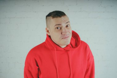 Yakışıklı olan bir tuğla duvar tarafından poz. Kırmızı kapüşonlu deli adam