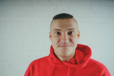 Yakışıklı olan bir tuğla duvar tarafından poz. Kırmızı kapüşonlu deli adam