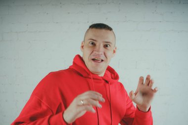 Yakışıklı olan bir tuğla duvar tarafından poz. Kırmızı kapüşonlu deli adam