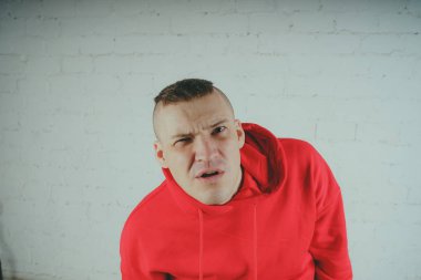 Yakışıklı olan bir tuğla duvar tarafından poz. Kırmızı kapüşonlu deli adam