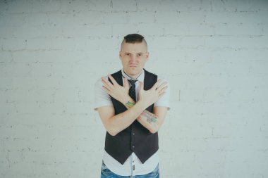 Beyaz duvara karşı poz duygusal ofis çalışanı ile bir dövme. Bir kravat adam kot pantolon ve beyaz gömlek giymiş.