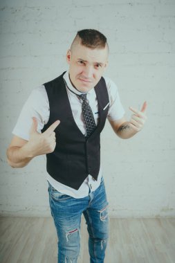 Beyaz duvara karşı poz duygusal ofis çalışanı ile bir dövme. Bir kravat adam kot pantolon ve beyaz gömlek giymiş.