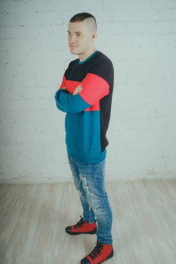 Yakışıklı olan bir tuğla duvara poz. Çizgili kazağı deli adam