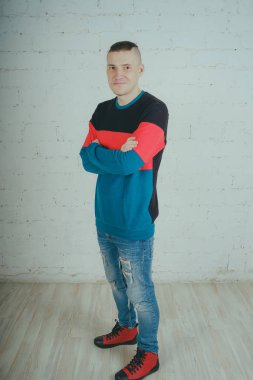 Yakışıklı olan bir tuğla duvara poz. Çizgili kazağı deli adam