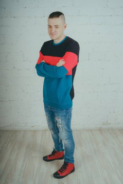 Yakışıklı olan bir tuğla duvara poz. Çizgili kazağı deli adam