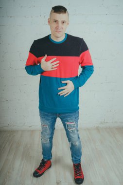 Yakışıklı olan bir tuğla duvara poz. Çizgili kazağı deli adam