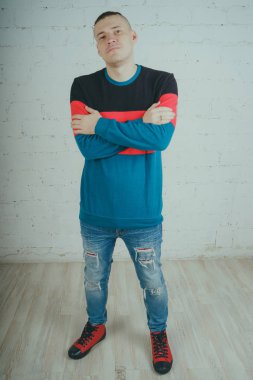 Yakışıklı olan bir tuğla duvara poz. Çizgili kazağı deli adam