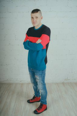 Yakışıklı olan bir tuğla duvara poz. Çizgili kazağı deli adam