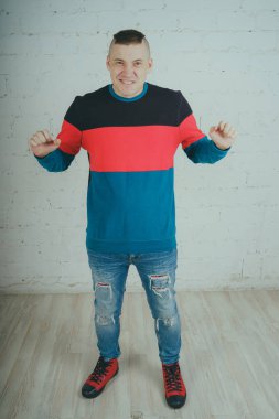 Yakışıklı olan bir tuğla duvara poz. Çizgili kazağı deli adam