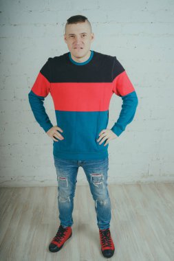 Yakışıklı olan bir tuğla duvara poz. Çizgili kazağı deli adam