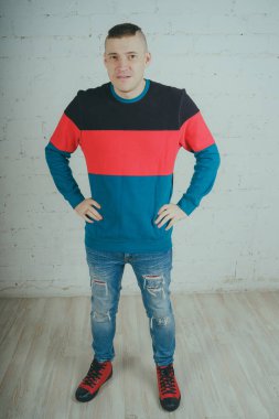 Yakışıklı olan bir tuğla duvara poz. Çizgili kazağı deli adam