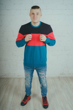 Yakışıklı olan bir tuğla duvara poz. Çizgili kazağı deli adam