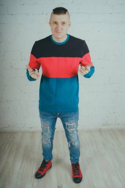 Yakışıklı olan bir tuğla duvara poz. Çizgili kazağı deli adam