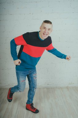 Yakışıklı olan bir tuğla duvara poz. Çizgili kazağı deli adam