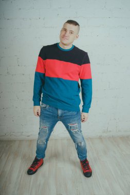 Yakışıklı olan bir tuğla duvara poz. Çizgili kazağı deli adam