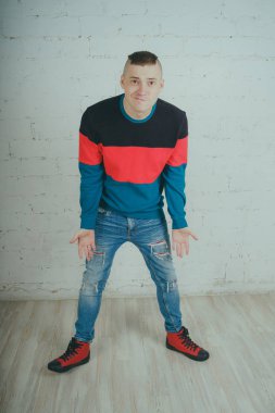 Yakışıklı olan bir tuğla duvara poz. Çizgili kazağı deli adam