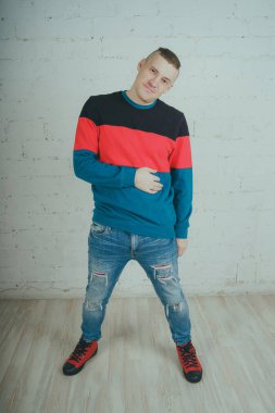 Yakışıklı olan bir tuğla duvara poz. Çizgili kazağı deli adam