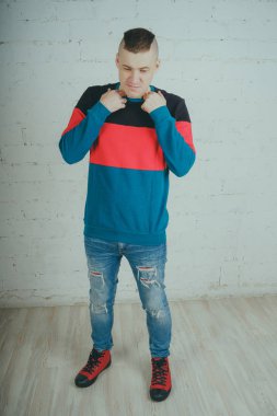 Yakışıklı olan bir tuğla duvara poz. Çizgili kazağı deli adam