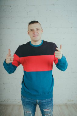 Yakışıklı olan bir tuğla duvara poz. Çizgili kazağı deli adam